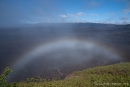 Der aufziehende Nebel formt sich zu einem Regenbogen über dem Kraterrand des 